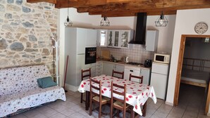 Een gezellige keuken met een eettafel, houten stoelen en een stenen muur.