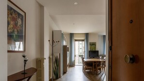 A hallway leading to a dining area with a table and chairs, a radiator, and a television. - GuestHost - Cozy apartment of 90 sqm, can accommodate up to 5 people, located on the sixth floor of a building with a lift (NOT suitable for disabled people).The property is located in an area well connected by public transport, the metro line B Piramid (Roma)