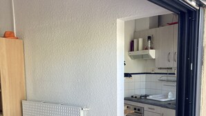 A compact kitchen with a dining area, featuring a radiator, a table, and a bench. - Chalet in a shady residence with swimming pool (Occitanie)