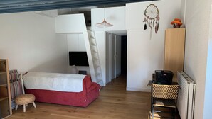 A bedroom with a red bed, a white wardrobe, a television, a dreamcatcher, and a ladder leading to a loft. - Chalet in a shady residence with swimming pool (Occitanie)