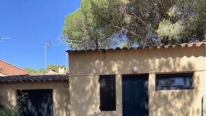 A building with a closed garage door, a small window, and a door. - Chalet in a shady residence with swimming pool (Occitanie)