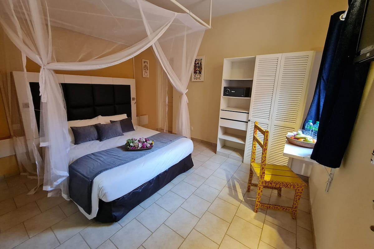 Een slaapkamer met een bed, een nachtkastje, een stoel, een kledingkast en een televisie.