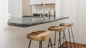 A kitchen with a marble countertop, a stainless steel faucet, and wooden bar stools. - Private Pool Oasis | 4BR Near Downtown Perry (Perry)