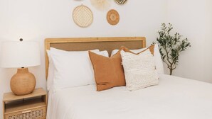 A bed with white bedding, a wooden headboard, a bedside lamp, and a nightstand with a woven basket. - Private Pool Oasis | 4BR Near Downtown Perry (Perry)