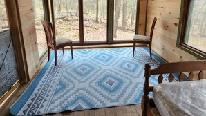 Eine Hütte mit einem großen Fenster, einem Bett und einem blauen Teppich mit Muster.