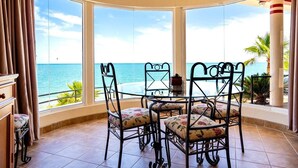 Una mesa redonda con sillas en una habitación con grandes ventanales con vistas al océano.