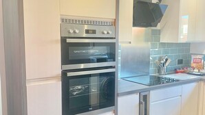 Una cucina moderna con mobili bianchi, elettrodomestici in acciaio inossidabile e piastrelle a parete.