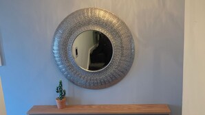 Un bagno moderno con uno specchio rotondo, un mobile contenitore in legno e un lampadario a soffitto.