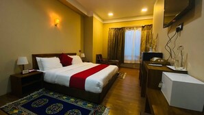 A hotel room with a bed, bedside tables, a desk, a chair, a TV, and a window with curtains. - Tsherim Resort (Paro)