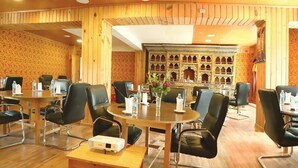 A conference room with round tables, black leather chairs, and a projector. - Tsherim Resort (Paro)