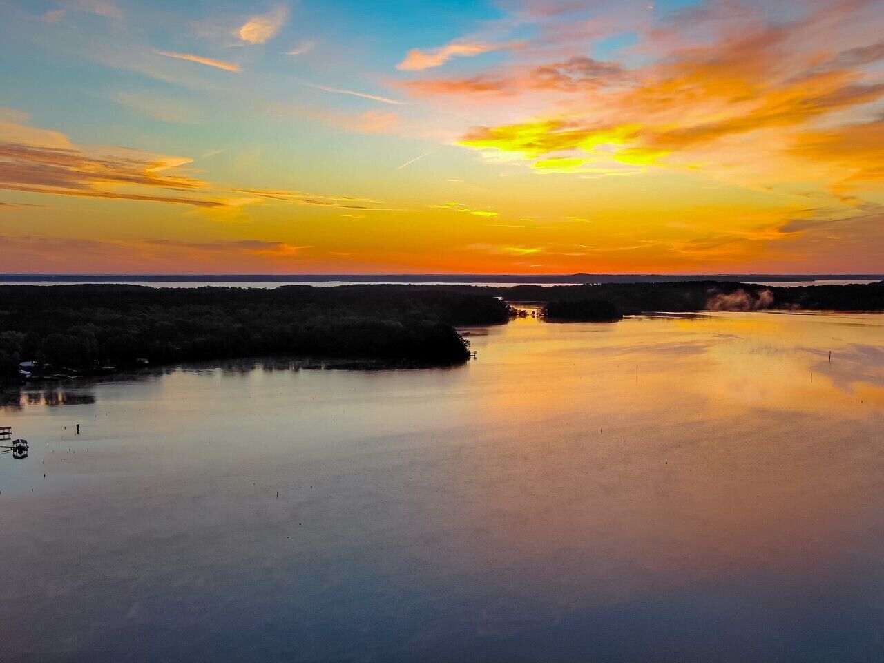 Een rustig wateroppervlak weerspiegelt een zonsondergang.