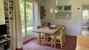 Un coin repas avec une table en bois, des chaises et un téléviseur posé sur une étagère.