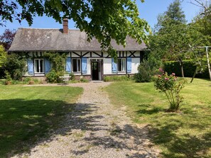A traditional half-timbered house with a gravel path leading to the entrance, surrounded by a well-maintained garden and trees. - Fleur Bleue, single storey farmhouse 2 km from the beach (Longueil)