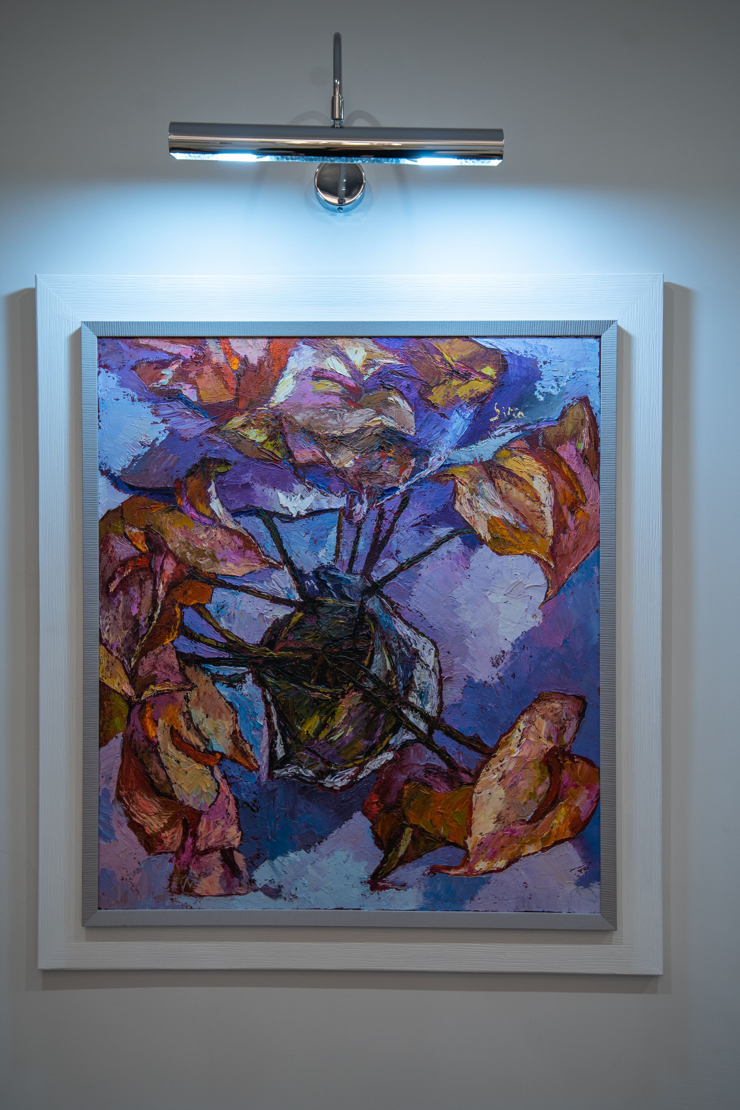 Un quadro incorniciato con fiori appeso al muro.
