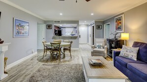 A spacious living room with a dining area, a ceiling fan, and a sofa with decorative pillows.