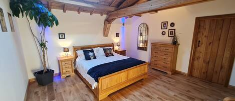 Une chambre à coucher avec un lit en bois, des tables de chevet, une commode et une grande plante en pot.