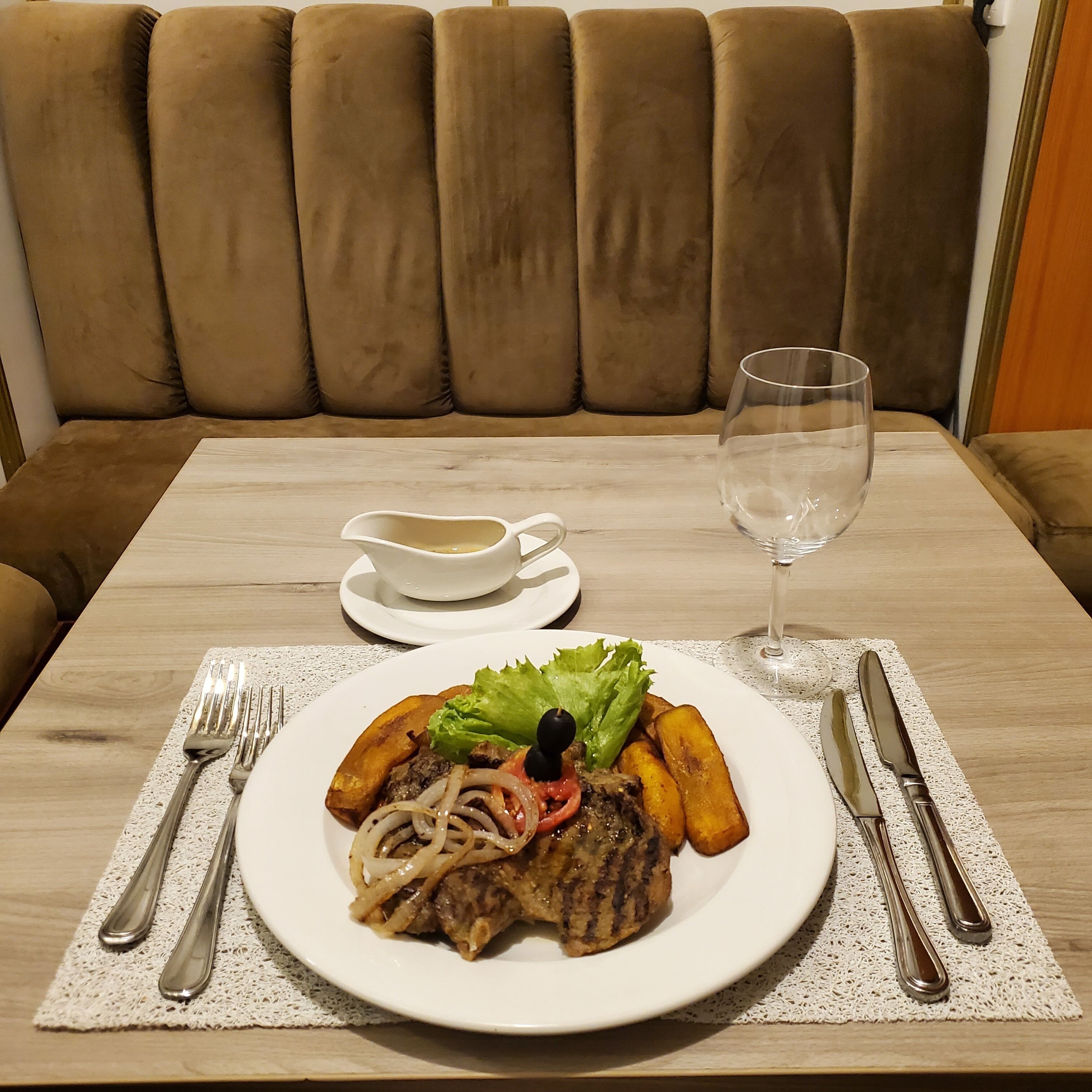 A dining table with a plate of food, a glass of water, and cutlery.