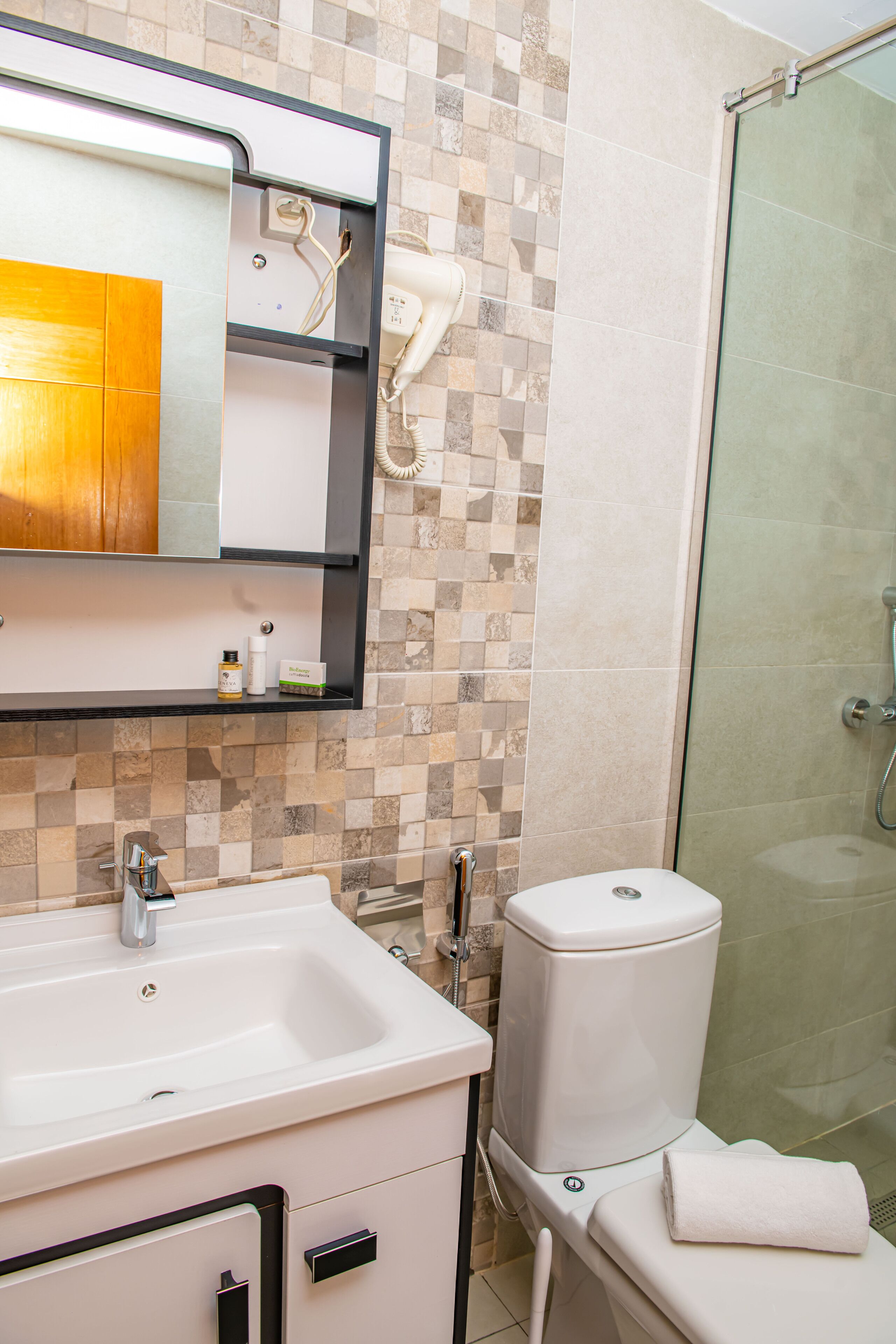 A bathroom with a white sink, a mirror, a toilet, and a shower area.