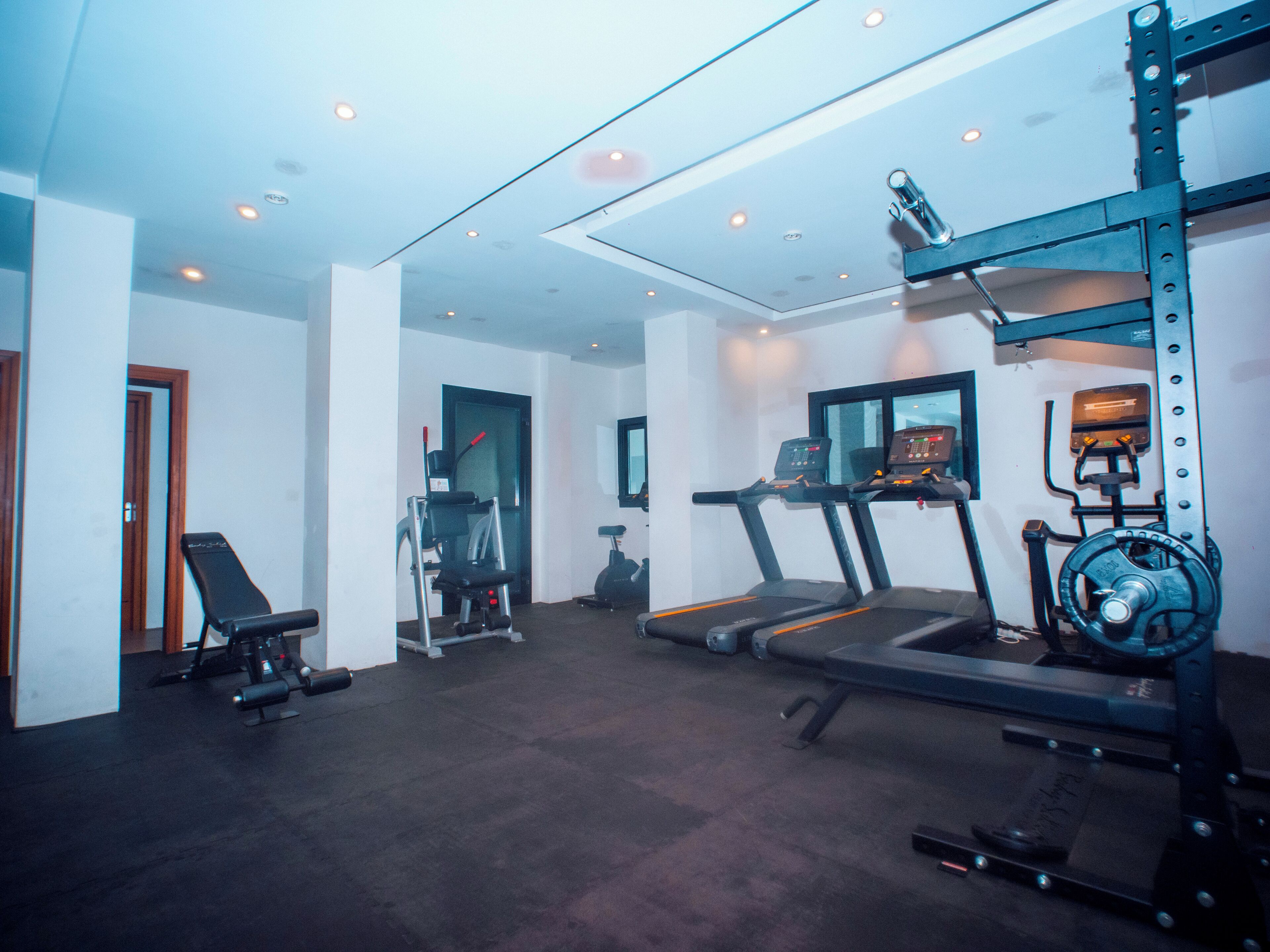 A gym with treadmills, a bench press, and weightlifting equipment.