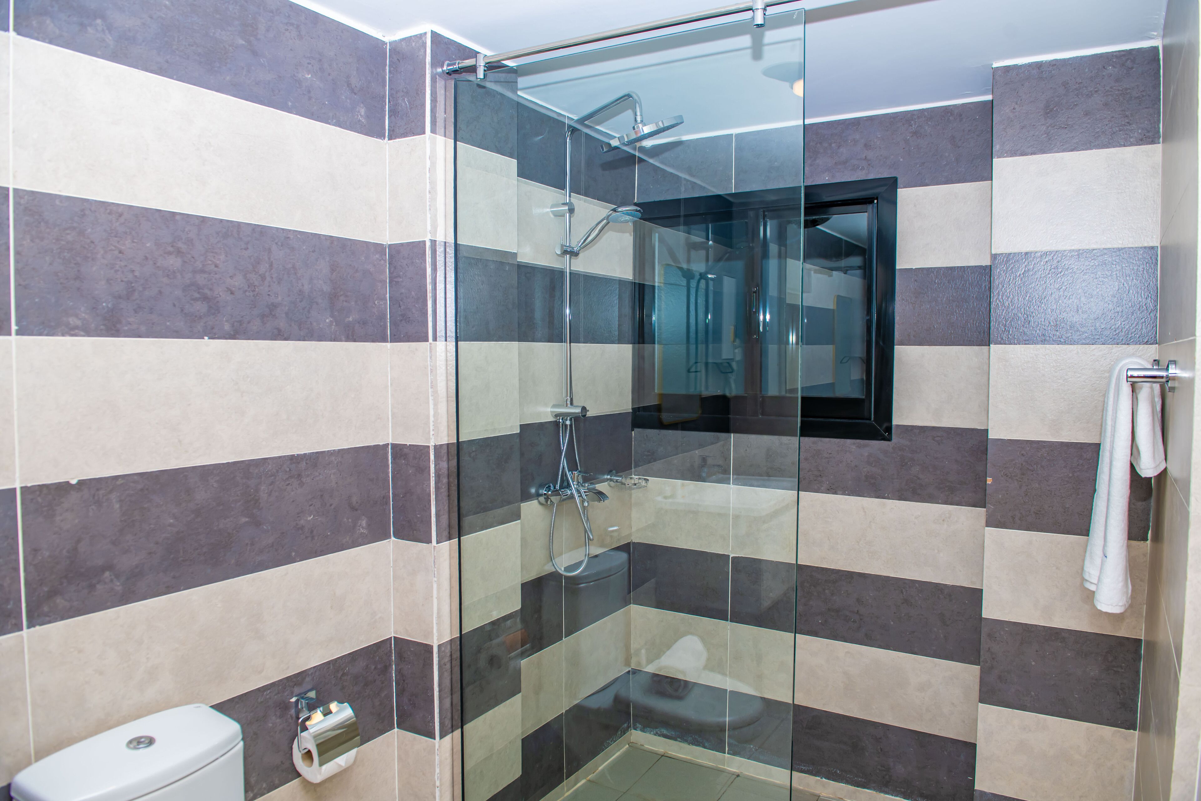 Un baño moderno con ducha de vidrio, inodoro y toallero.