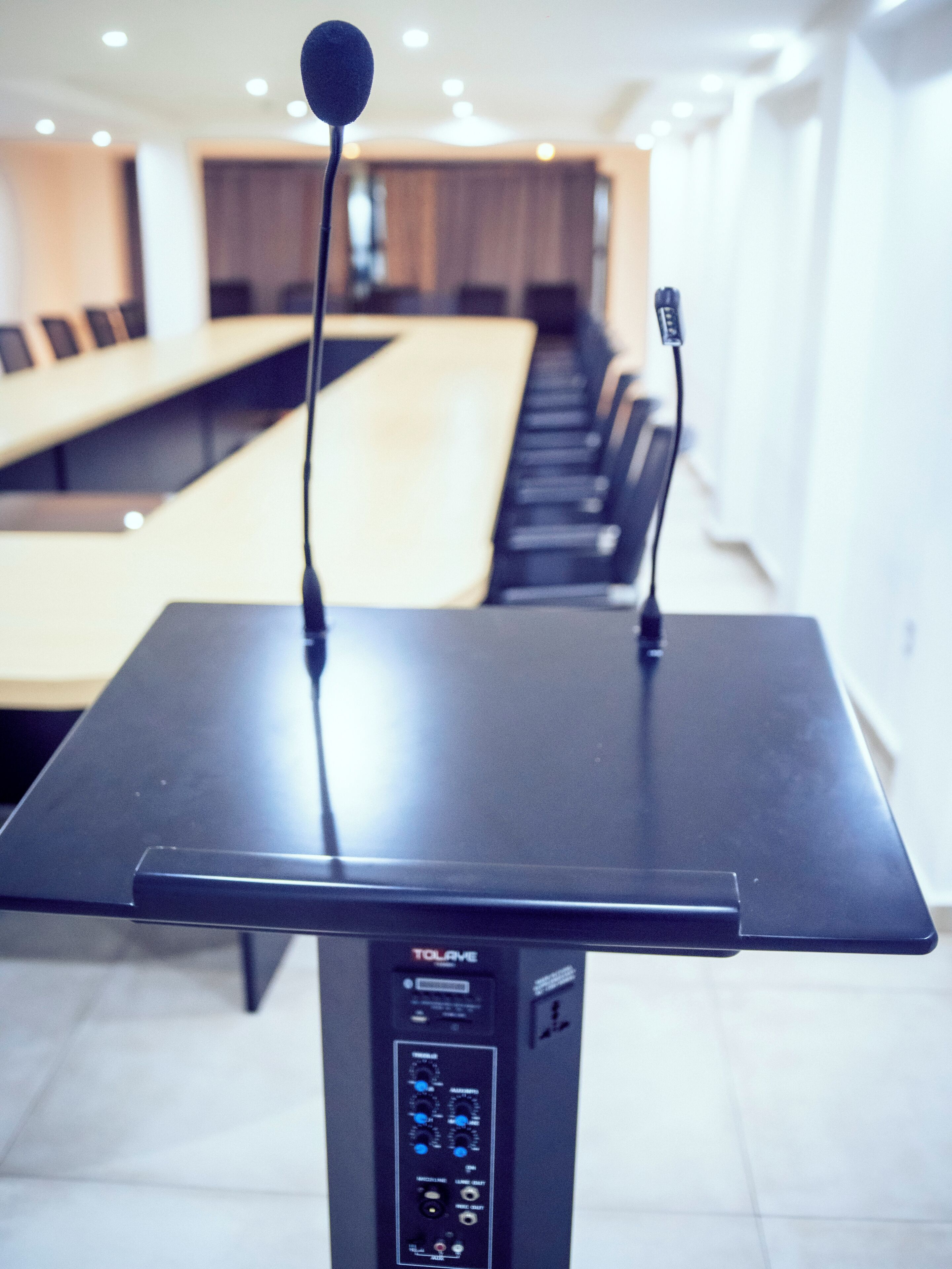 A conference table with a microphone stand and a control panel.