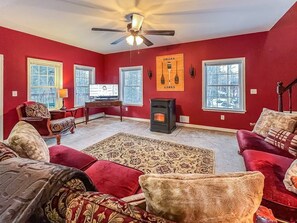 A living room with red walls, a fireplace, and a ceiling fan.