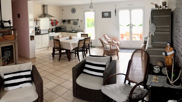 A spacious living area with a dining table, wicker furniture, and a kitchen in the background. - Plain pied at eckmuhl lighthouse  (Penmarc'h)