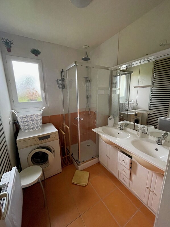A compact bathroom with a washing machine, a glass-enclosed shower, and a double sink vanity. - Plain pied at eckmuhl lighthouse (Penmarc'h)