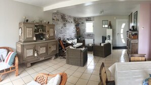 A spacious living area with a large wooden cabinet, wicker furniture, and a stone wall. - Plain pied at eckmuhl lighthouse  (Penmarc'h)