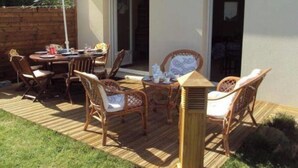 An outdoor patio with a wooden deck, wicker furniture, and a table set for dining. - Plain pied at eckmuhl lighthouse  (Penmarc'h)