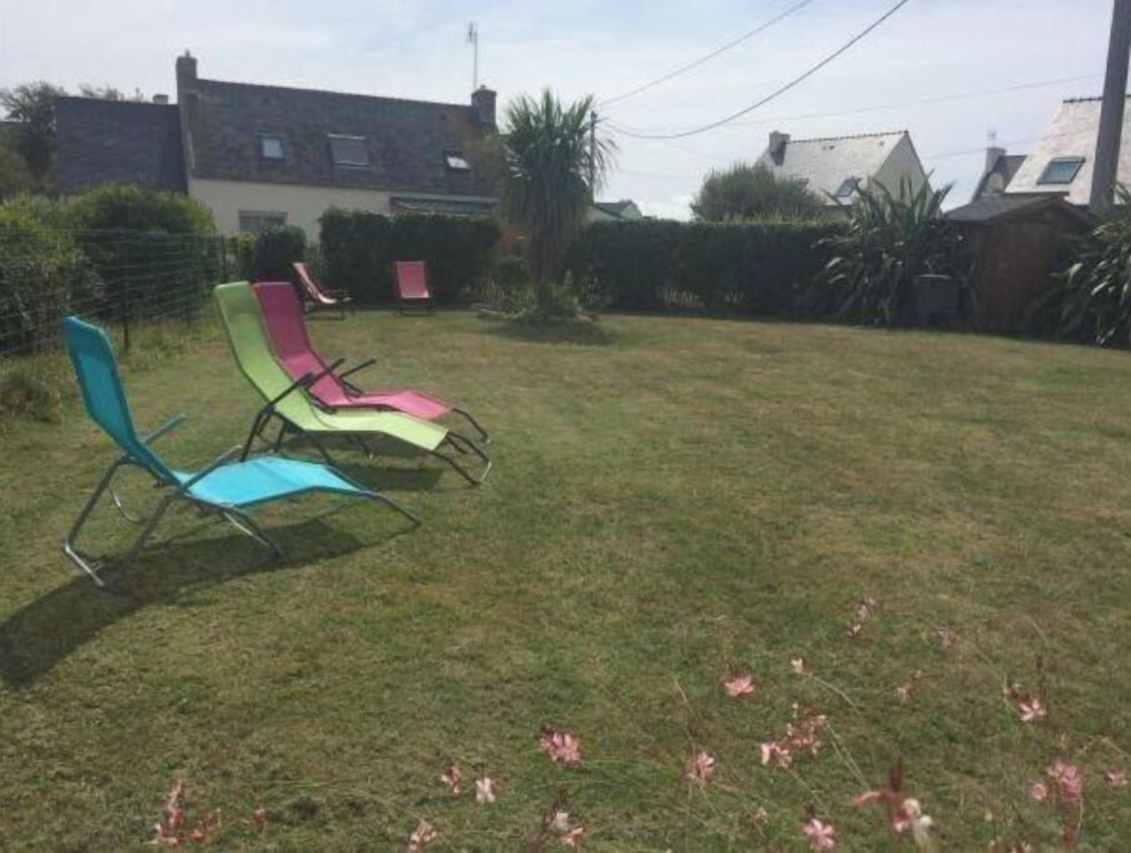Une cour arrière verdoyante avec deux chaises de jardin colorées.