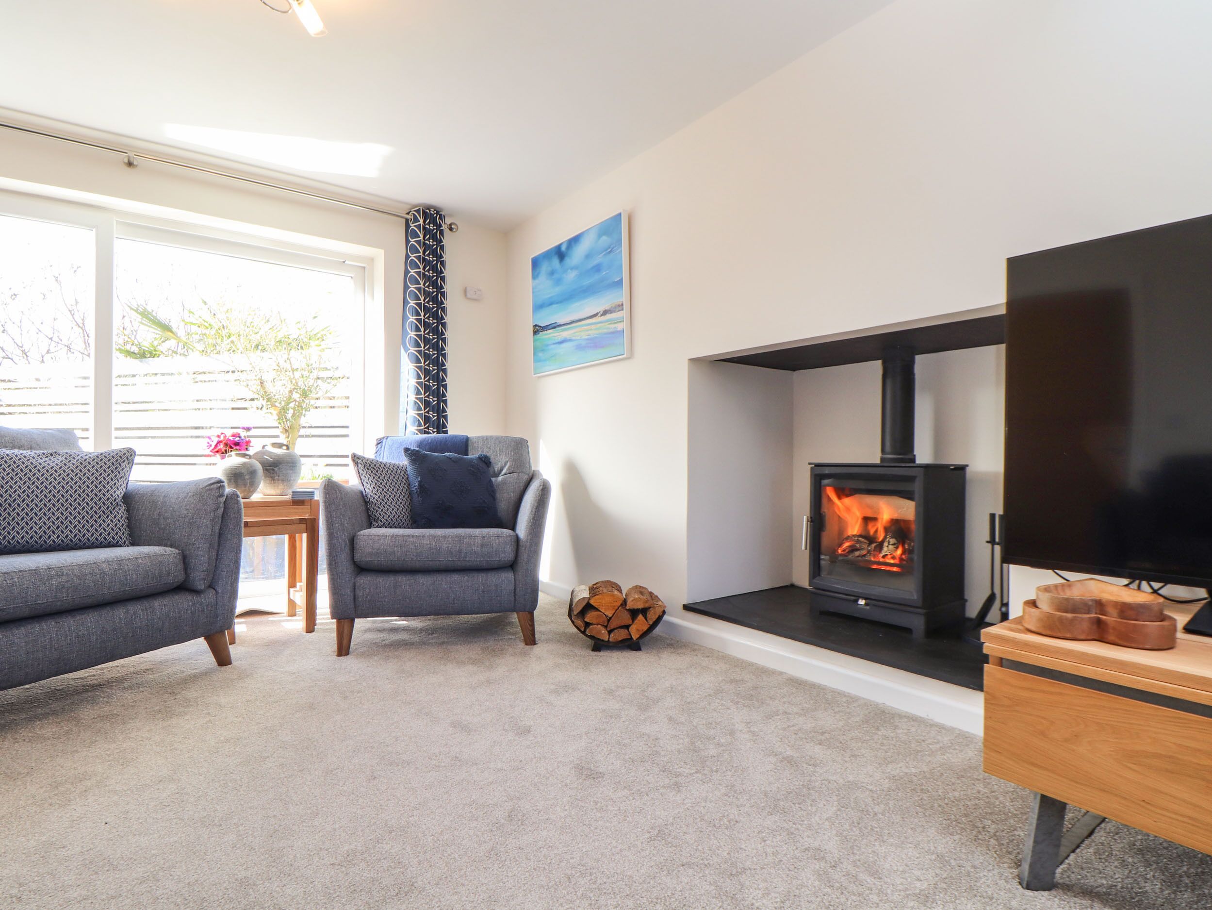 A living room with a fireplace, a sofa, a chair, and a TV stand.
