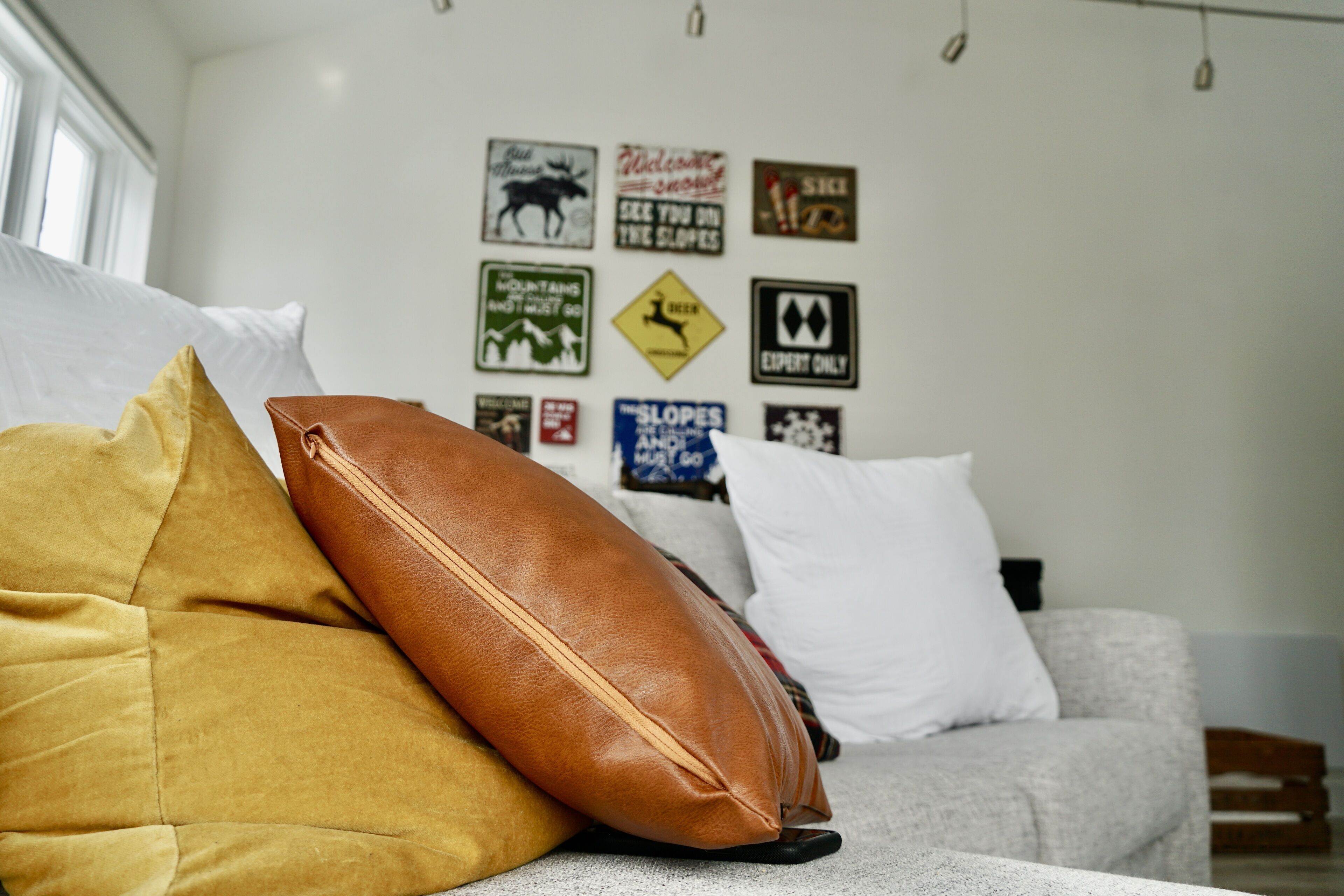Una habitación con sofá, almohadas y una pared decorada con varios letreros.