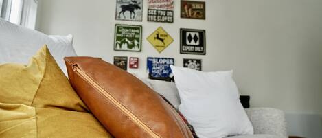 Una habitación con sofá, almohadas y una pared decorada con varios letreros.
