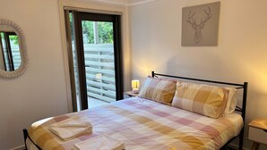 A hotel room with a bed, a window with curtains, a wall-mounted mirror, a framed artwork, and a bedside table with a lamp. - Relaxing Oasis in Bruce -1bd Apt (Bruce)