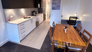 A modern kitchen with white cabinets, a wooden dining table, and a view into the dining area. - Relaxing Oasis in Bruce -1bd Apt (Bruce)