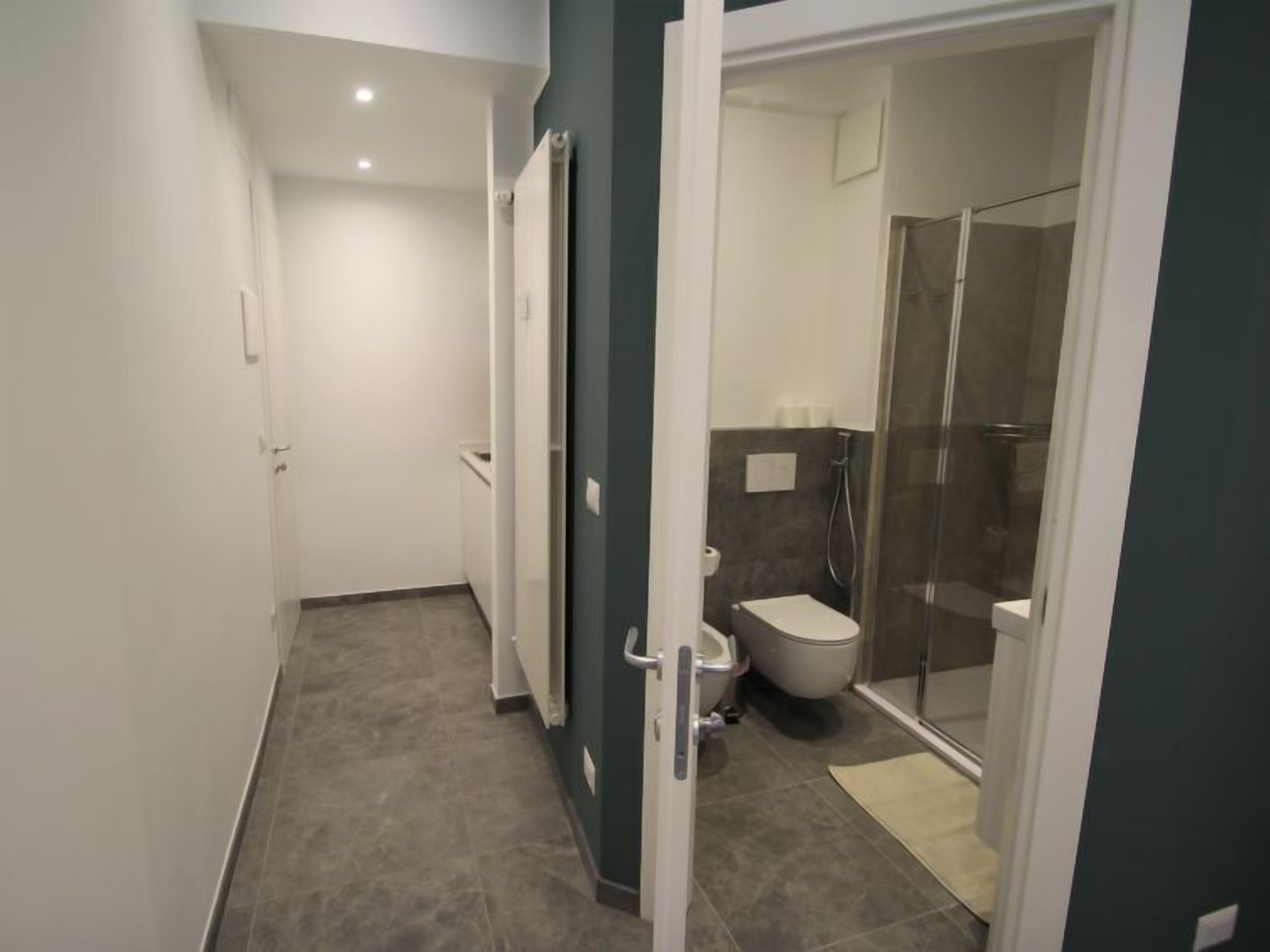 Casa de banho moderna com sanita, chuveiro e área de duche com parede de vidro.