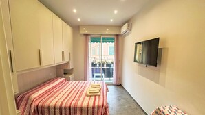 Quarto com cama, televisão e janela com vista para edifícios.