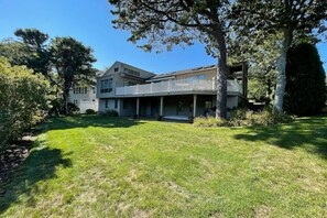 A two-story house with a covered porch and a large lawn.