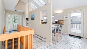 Une cuisine moderne avec un coin repas, un escalier et une vue sur l’extérieur.