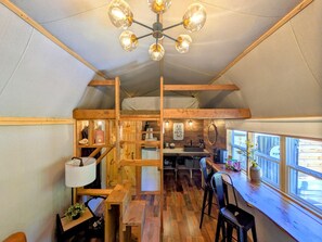 Un interior acogedor de madera con comedor, cocina y un dormitorio en lo alto.
