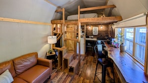 Ein gemütliches Blockhaus-Interieur mit einer Holzespeisegruppe, einer Couch und einer Küche mit Fenster.