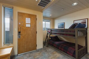 A bunk bed room with a wooden door, a window, and a ladder.