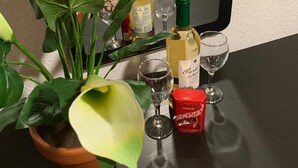 Una mesa con una planta en maceta, botellas de vino, copas y una caja de bombones Lindor.