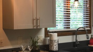 Une cuisine avec des meubles blancs, un plan de travail noir et des luminaires suspendus.