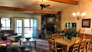 A cozy living room with a fireplace, wooden dining table, and comfortable seating. - Lake view two bedroom, two bath Harbor North luxury cottage with private hot tub overlooking Lake Ouachita. by RedAwning (Mount Ida)