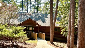 A rustic log cabin with a wooden deck and a covered porch. - Lake view three bedroom, three bath Harbor North luxury cottage with private hot tub overlooking Lake Ouachita. by RedAwning (Mount Ida)