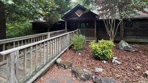 A wooden cabin with a porch and a wooden deck. - Lake view three bedroom, three bath cottage with private hot tub overlooking Lake Ouachita. by RedAwning (Mount Ida)