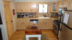A kitchen with wooden cabinets, a sink, a stove, and a refrigerator. - Lake view two bedroom, two bath log-sided cottage with private hot tub overlooking Lake Ouachita. by RedAwning (Mount Ida)