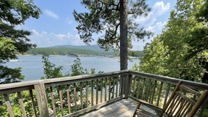 A wooden deck with a bench overlooking a lake, surrounded by trees and hills. - Lake view two bedroom, two bath loft, log-sided cottage with private hot tub overlooking Lake Ouachita. by RedAwning (Mount Ida)